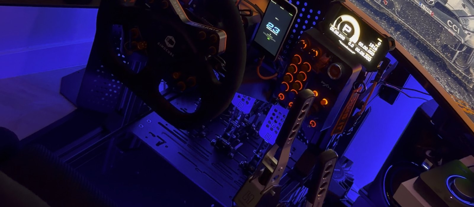 Adam's rig at night: wheel, pedals and button boxes under blue light